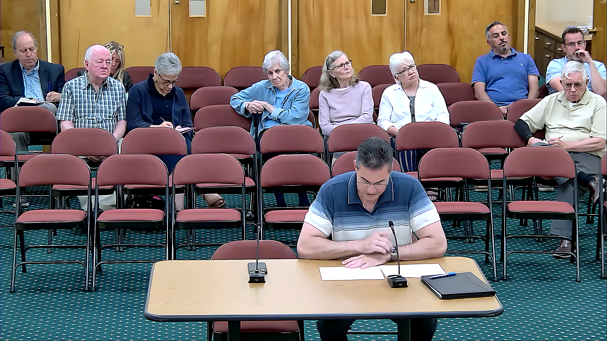 A speaker presents during discussion of a site plan for revised EV charging station locations at Hudson Condos.